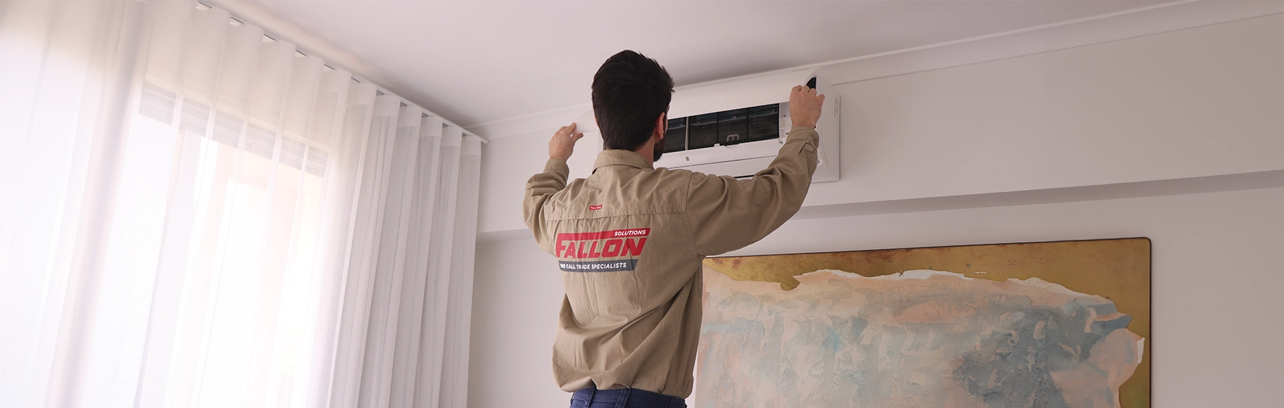 Fallon Solutions air conditioning technician reinstalling a filter cover after conducting a system clean.
