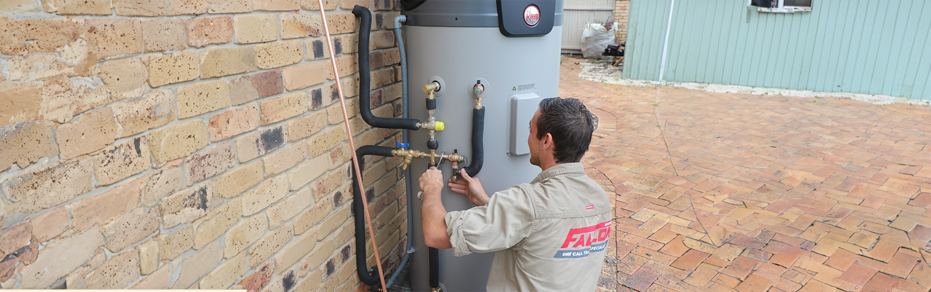 Fallon Solutions master hot water plumber installing a Rheem hot water system outside.